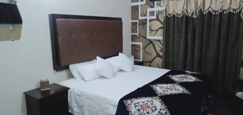 a bedroom with a bed with white sheets and pillows at Homewood Suite - Rooms & Appartments in Lahore