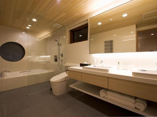 een badkamer met 2 wastafels, een toilet en een douche bij Seshu Chalet in Niseko