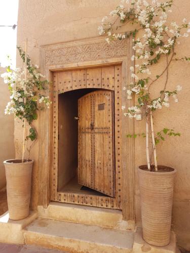 a door in a wall with two plants in vases at Tagadert Lodge in Oumnas