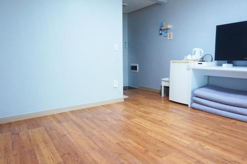 a living room with a wooden floor and a flat screen tv at Naksanstay in Yangyang