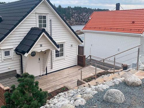 une maison blanche avec une terrasse en bois à côté d'un bâtiment dans l'établissement 8 person holiday home in Urangsv g, à Ervik