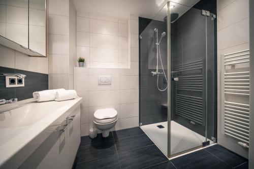 uma casa de banho com um WC e uma cabina de duche em vidro. em Appartement AROSA by Schladming-Appartements em Schladming