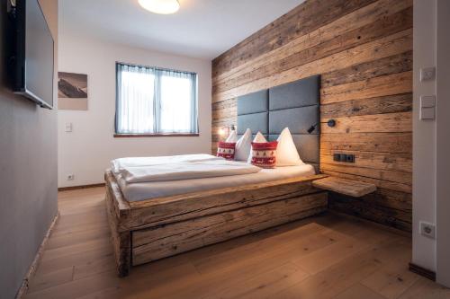 1 dormitorio con 1 cama con pared de madera en Appartement AROSA by Schladming-Appartements, en Schladming