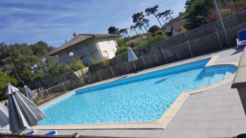 une grande piscine bleue en face d'une clôture dans l'établissement Appartement à deux pas de l ocean, à Moliets-et-Maa