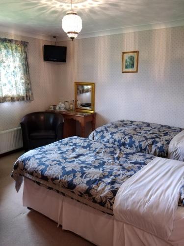 a bedroom with a bed and a chair and a desk at Alltyfyrddin Farm Guest House at The Merlin's Hill Centre in Carmarthen
