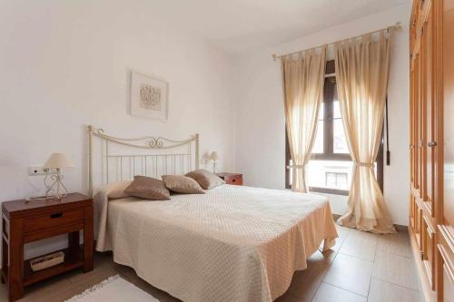 een witte slaapkamer met een bed en een raam bij casa jaramar in Sanlúcar de Barrameda
