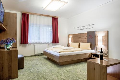 a bedroom with a large bed and red curtains at DIE BARBARA Appartements & Zimmer in Schladming