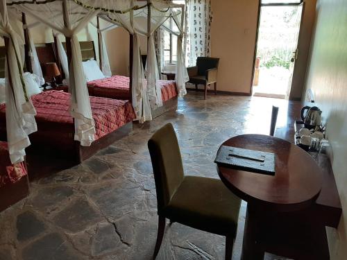 a hotel room with two beds and a table and a table at AA Lodge Amboseli in Amboseli