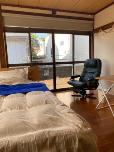 een slaapkamer met een bed, een bureau en een stoel bij 民泊ドリームルーカー in Haranomachi