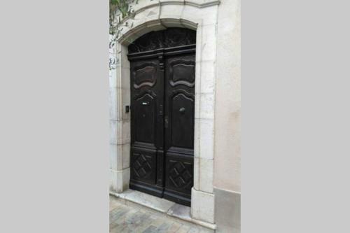 una gran puerta negra en un edificio en F1 RDC indépendant dans bastide du XVème en Brignoles