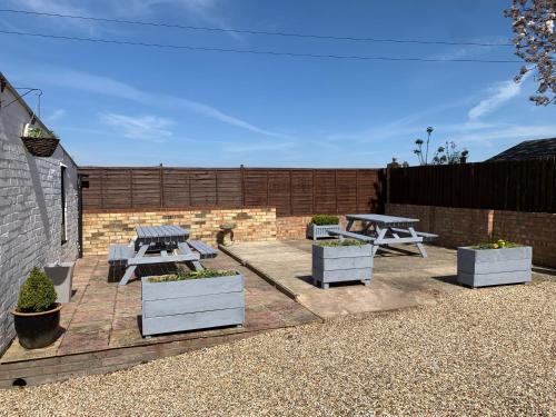 a patio with three picnic tables and potted plants at Eclipse Apartment No 2 in Newmarket