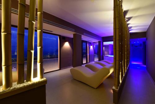 a room with a balcony with white furniture and purple lighting at Hotel Parco Degli Aromi Resort & SPA in Valderice