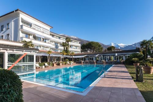 a large swimming pool in front of a building at Parkhotel Delta, Wellbeing Resort in Ascona