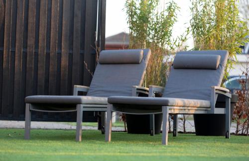 two lounge chairs sitting on the grass in a yard at Hip huisje aan de Maas in Lith