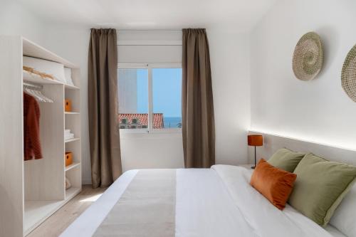 a bedroom with a white bed and a window at Apartamentos Venecia in Lloret de Mar