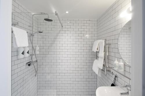 a white tiled bathroom with a shower and a sink at Arkösunds Hotell in Arkösund