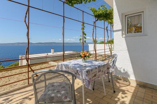 a table and chairs on a balcony with a view of the water at Rooms Sani in Brela