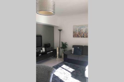 a living room with a couch and a tv at Beautiful Apartment Palames in Sesimbra