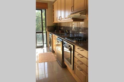 a kitchen with wooden cabinets and a stove top oven at Beautiful Apartment Palames in Sesimbra