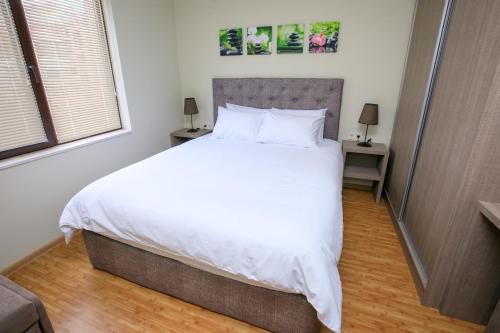 a bedroom with a large bed with white sheets and pillows at Feel at Home in Sandanski