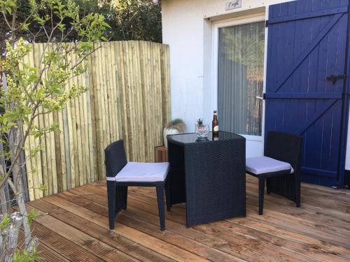a table and chairs on a deck with a blue door at Hôtel Des Argousiers in Ambleteuse