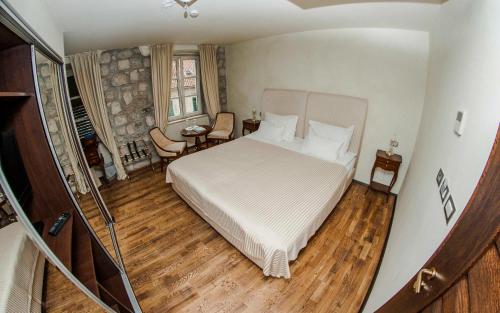 a bedroom with a large white bed and wooden floors at Boutique Hotel Astoria in Kotor