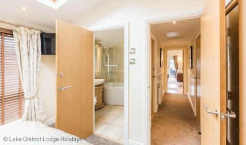 un bagno con porta che si apre su un bagno con vasca di Elder Lodge a Windermere
