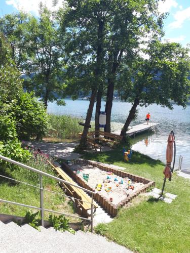 a garden with a sandbox on the shore of a lake at ANNA Seeblick Appartement, Haus Hänsel&Gretel am Ossiachersee mit direktem Seezugang, Hallenbad in Bodensdorf