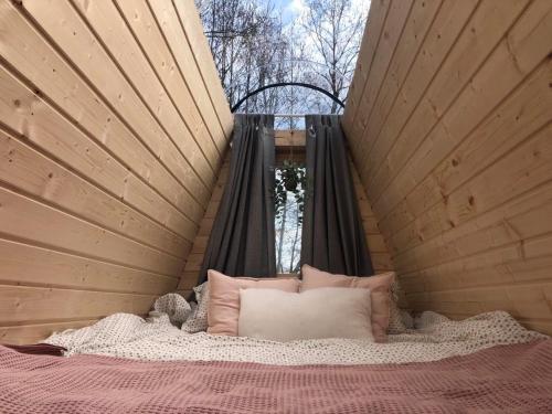 a bed in a room with a window and a bed with pillows at Niiralan Tila : Starlite Cabin in Laitila