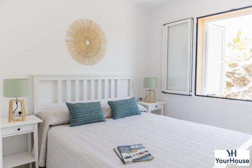 a white bedroom with a bed and a window at YourHouse Es Niu, apartment in Puerto de Sóller in Sóller