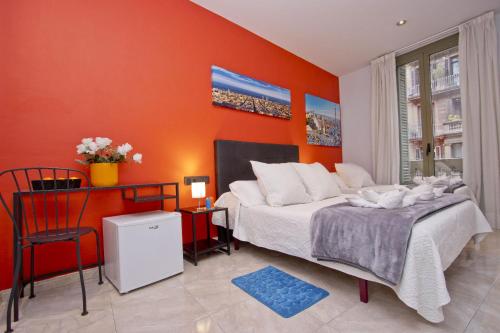 a bedroom with orange walls and a bed and a chair at Barcelona City Centre Hostal in Barcelona