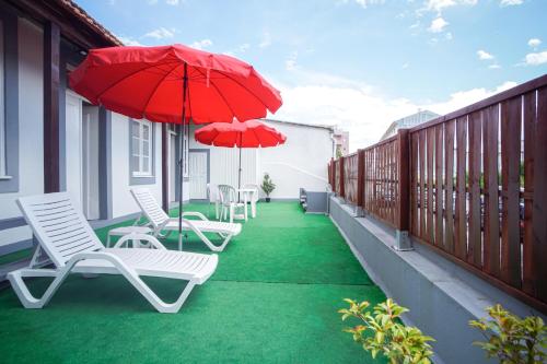 a patio with chairs and umbrellas on a balcony at Alojamento Duque D`Avila in Aveiro