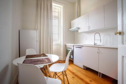 a kitchen with white cabinets and a table and chairs at Alojamento Duque D`Avila in Aveiro