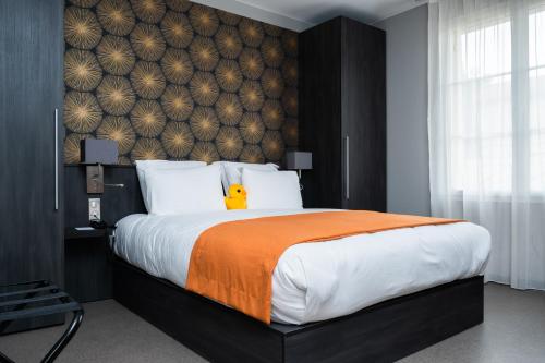 a bedroom with a large bed with an orange blanket at Best Western Plus Le Canard sur le Toit in Colomiers