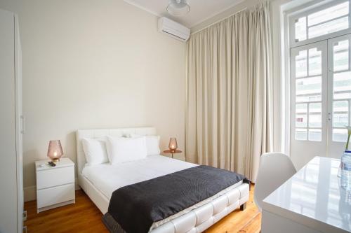 a white bedroom with a bed and a window at Alojamento Duque D`Avila in Aveiro