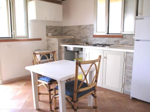 una cucina con tavolo e sedie bianchi di Baia degli ulivi a Diamante