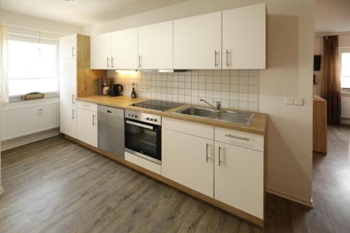 a kitchen with white cabinets and a sink at Ferienhof Neukirchinger in Tiefenbach