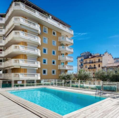 un appartement avec une piscine en face d'un bâtiment dans l'établissement Résidence Les domes, Piscine, à Nice