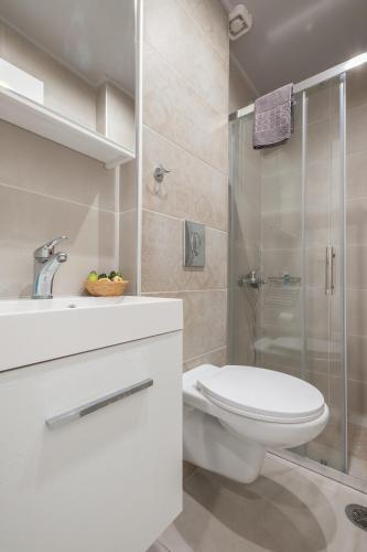 a white bathroom with a toilet and a shower at Armonia Rooms in Myrina