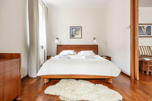 um quarto com uma cama com uma colcha branca e um tapete em Victus Apartamenty, Apartament Biały Piasek em Sopot