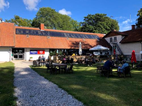 eine Gruppe von Personen, die vor einem Gebäude an Tischen sitzen in der Unterkunft Ekegården in Havdhem