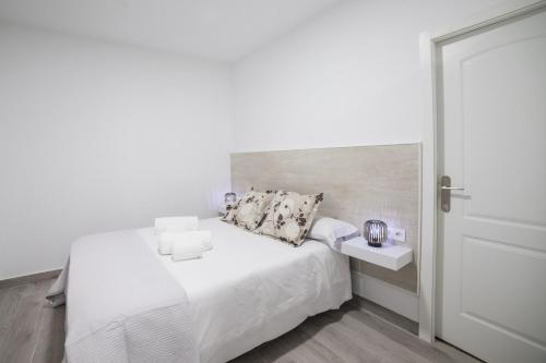 ein weißes Schlafzimmer mit einem weißen Bett und einer weißen Tür in der Unterkunft Moonkey - Apartamento Amaralba B in Alicante