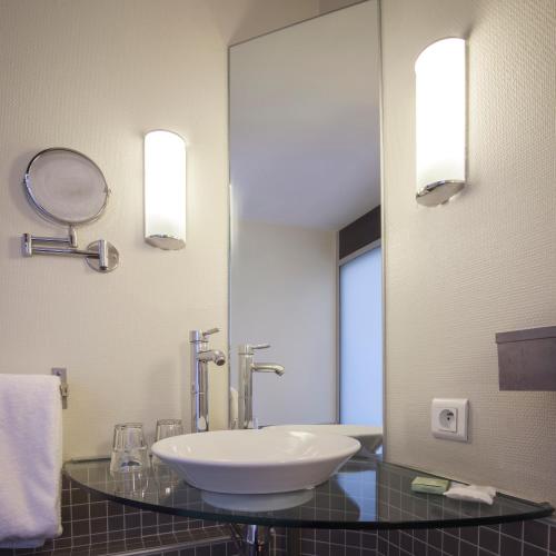 a bathroom with a sink and a large mirror at Best Western Plus Le Canard sur le Toit in Colomiers