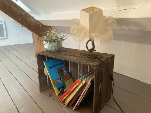 uma prateleira de madeira com um livro e uma planta sobre ele em Chambres chez l'habitant Capucine em Honfleur
