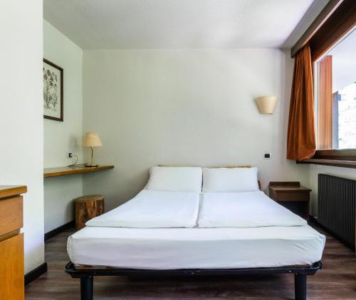 a white bed in a room with a window at Ambiez Residencehotel in Madonna di Campiglio