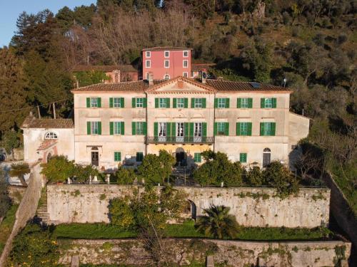 een groot wit huis met groene ramen op een heuvel bij Agriturismo Villa Cavallini in Camaiore