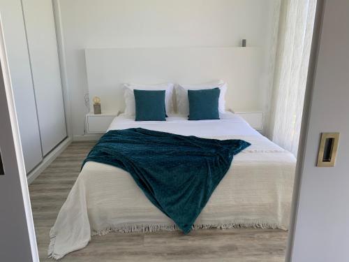 a bedroom with a large white bed with blue pillows at northsouthviescasinha in Calheta