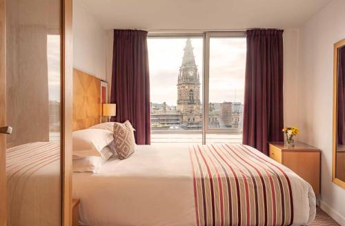 a bedroom with a bed and a window with a clock tower at PREMIER SUITES Liverpool in Liverpool