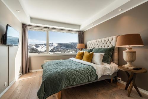 a bedroom with a bed and a large window at Ustedalen Resort Leiligheter in Geilo