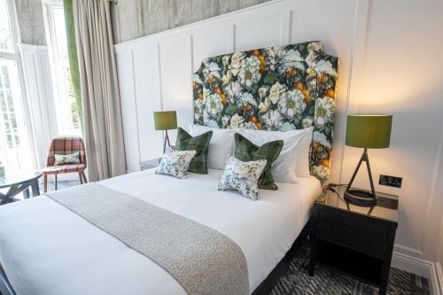 a bedroom with a large bed with a painting on the wall at Dunkeld House Hotel in Dunkeld